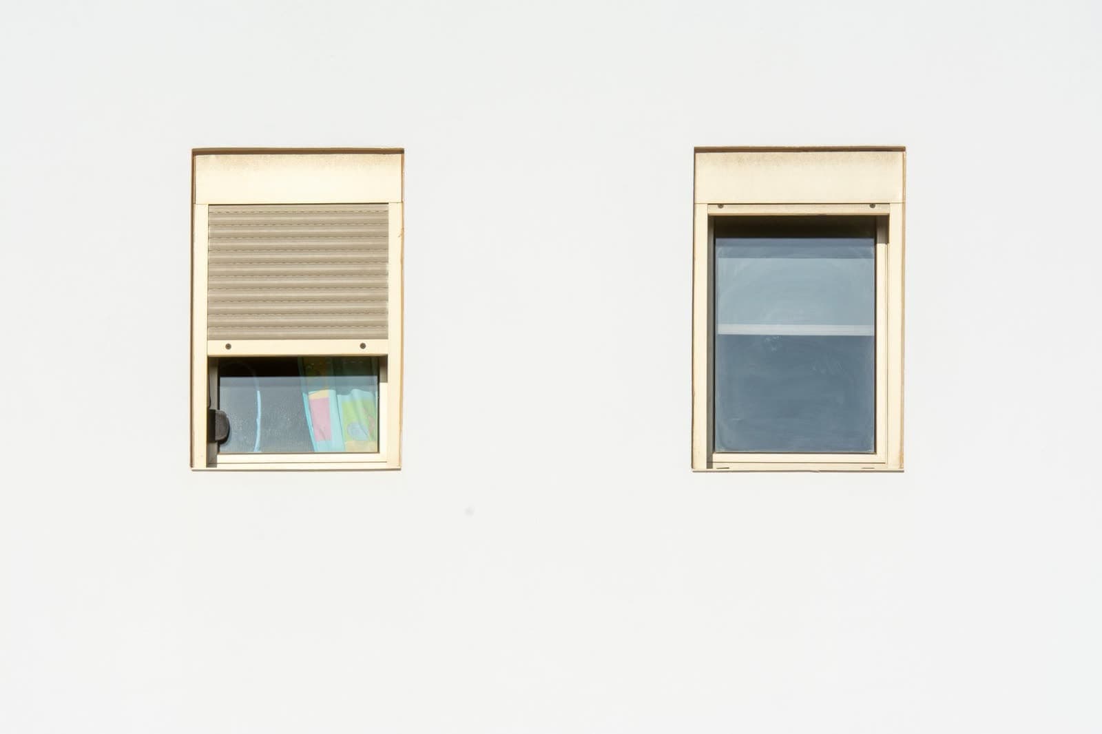 Dos huecos de ventana con el cajón de la persiana a la vista y una de ellas bajada hasta la mitad
